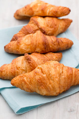 Tasty buttery croissants on old wooden table.