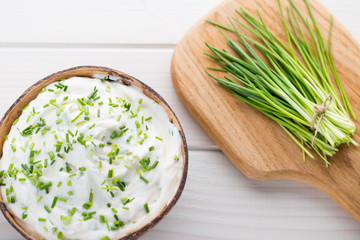 Bowl of cream cheese with green onions, dip sauce on wooden table.