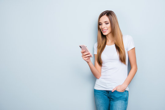 Portrait with copyspace empty place of pretty trendy girl having smart phone in hands checking email chatting with friends using 5G wi-fi internet isolated on grey background