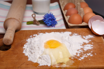 pizza or pie recipe ingridients, food flat lay on wood kitchen table background. baking ingredients. Bowl, eggs, milk, flour, eggbeater, rolling pin and eggshells