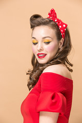 Beautiful young woman with pinup make-up and hairstyle. Studio shot on pastel background