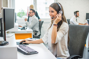 Young smiling operator woman agent with headsets working in a call center.