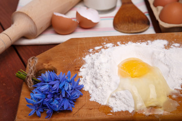pizza or pie recipe ingridients, food flat lay on wood kitchen table background. baking ingredients. Bowl, eggs, milk, flour, eggbeater, rolling pin and eggshells