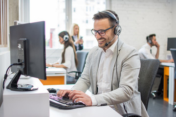 Smiling customer service executive with headset working in call center.