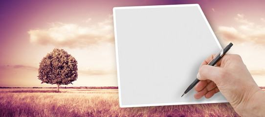 Hand writing with a pencil on a blank sheet against a tuscany rural scene (Italy) - image with copy...