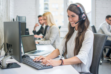 Attractive young woman working at call center office with her colleagues.