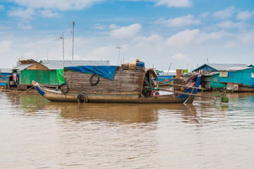 A sampan-like boat, including a small shelter with a curved roof made of wood and thatch that might be a permanent habitation, is anchored in Cambodia's floating village Chong Kneas on Tonle Sap Lake.