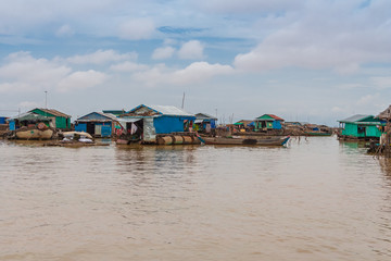 View of the floating houses in Cambodia's floating village Chong Kneas on Tonle Sap Lake. The houses made of metal plates are floating on wooden platforms with empty barrels.