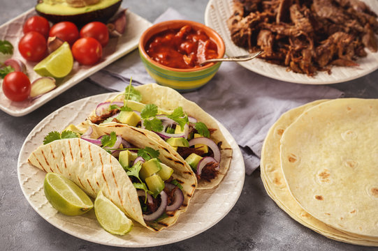 Pulled porc carnitas with avocado and red onion on tortillas. mexican food.