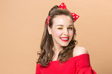 Beautiful young woman with pinup make-up and hairstyle. Studio shot on pastel background