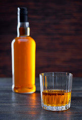 Whiskey on a  black wooden table.Silhouette of a bottle.