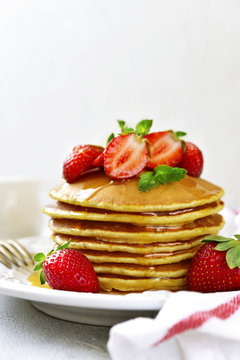 Stack of delicious pancakes with maple syrup and fresh strawberry for a breakfast.