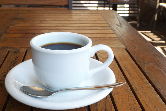 カフェのテラス席のコーヒー - A cup of coffee on the table at the outdoor wooden terrace