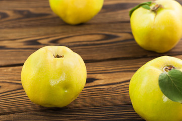 Scattered whole fresh ripe quinces on old weathered rustic brown wooden table with copy space