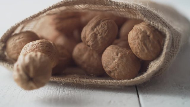 Walnuts in shell rolling out of burlap bag. Shot with high speed camera, phantom flex 4K. Slow Motion.