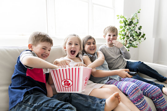 Child Group Eating Popcorn Together On Sofa