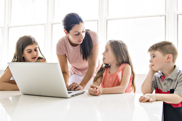 Fototapeta premium Teacher with a group of school children with laptop on the front