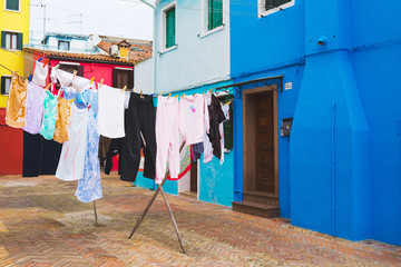 Fototapeta na wymiar Burano - Italian colorful island. Washing clothes drying on the rope in the yard 