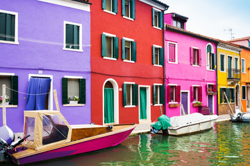 Fototapeta na wymiar Colorful houses and yachts in island Burano, Venice, Italy. Bright summer rainbow colours..