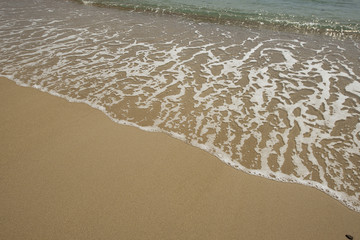 Shore of the beach where you can see foam on the sand. Summer.
