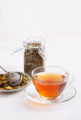Herbal tea in glass cup on white table.