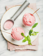 Healthy low calorie summer dessert. Homemade strawberry yogurt ice cream with fresh mint in glasses over light grey marble table background, top view. Clean eating, dieting food concept