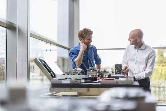 Two smiling men working on product in company