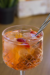 Cocktail with vodka, strawberries and lemon in glass on the bar
