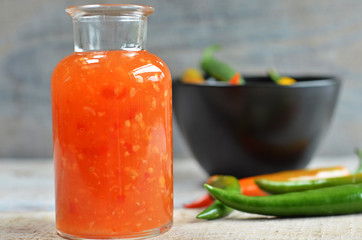 Sweet and sour sauce in a glass bottle on wood