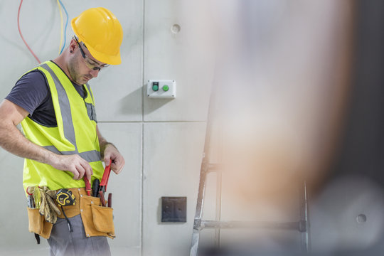 Electrician taking tools out of belt on construction site