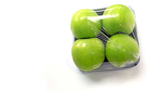 Apple is wrapped in clear plastic on a white background, leaving space.