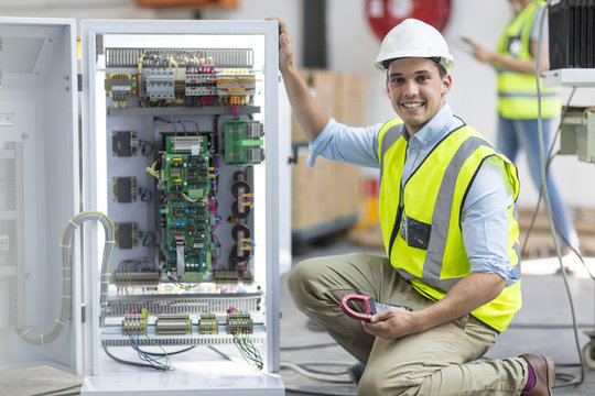 Portrait of smiling technician working on a box with circuit boards