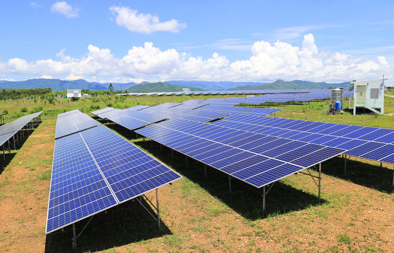 On Ground Solar Farm under Blue and Cloudy Sky Mountain Background