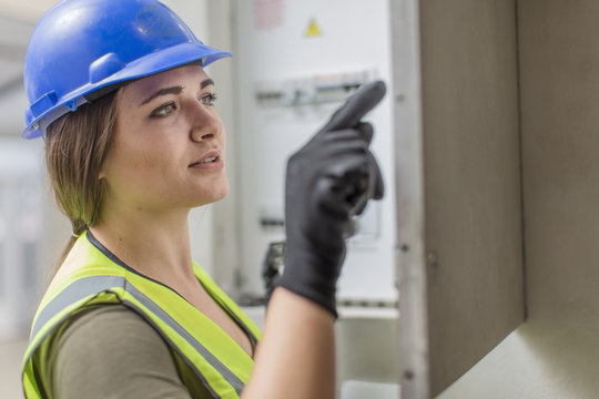Young female electrician working at fuse box