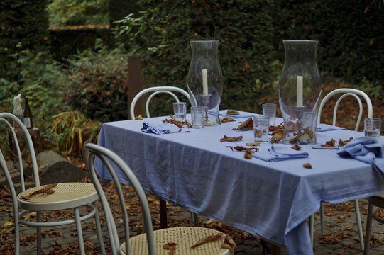 Table set outside dinner party table, glass, day after with candles and white chairs