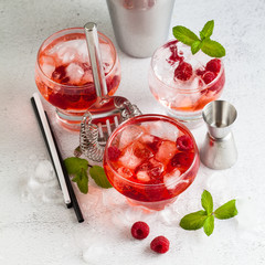 summer alcoholic drink with raspberry liqueur, ice and leaves of fresh mint on the table. bar accessories.