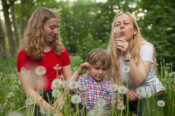 Mother blowing a dandelion outdoors. © Aitor Diago
