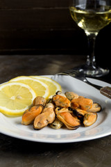 Mussels boiled on a white plate with lemon.