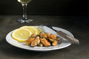 Mussels boiled on a white plate with lemon.