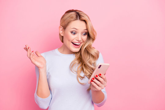 Portrait of wondered woman, excited student, shocked girlfriend having smart phone cellphone in hands watching picture video reading news isolated on pink background