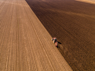 Obraz premium Aerial shot of a farmer plowing stubble field