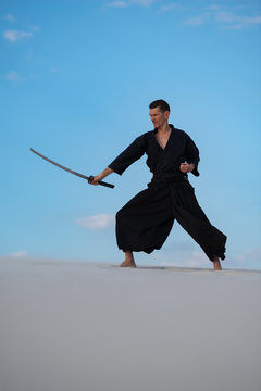 Man is training Japanese martial arts in desert