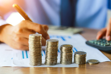 Close up,of people hand putting the coins on the table in his office in finance,investment,saving...