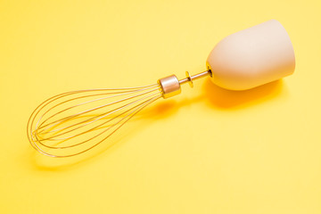 Stainless steel balloon whisk on yellow background
