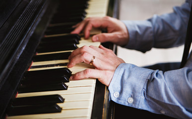 Close-up of male hands playing piano.With wedding ring.