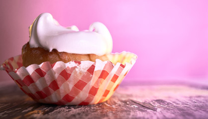 Cupcake with cream on a pastel background on a wooden table