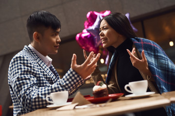 Couple screeches in coffee shop at table.