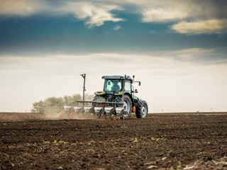 Farmer seeding, sowing crops at field. Sowing is the process of planting seeds in the ground as part of the early spring time agricultural activities.