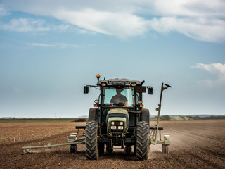 Farmer seeding, sowing crops at field. Sowing is the process of planting seeds in the ground as part of the early spring time agricultural activities.