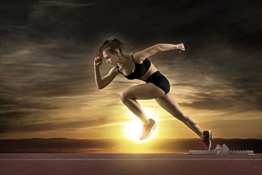 Woman Sprinter Leaving Starting Blocks On The Athletic Track